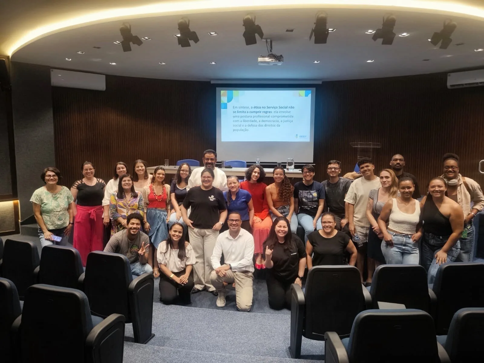 Participantes da aula sobre Ética e Trabalho Profissional reunidos em um auditório, diante de uma tela com princípios da ética no Serviço Social.